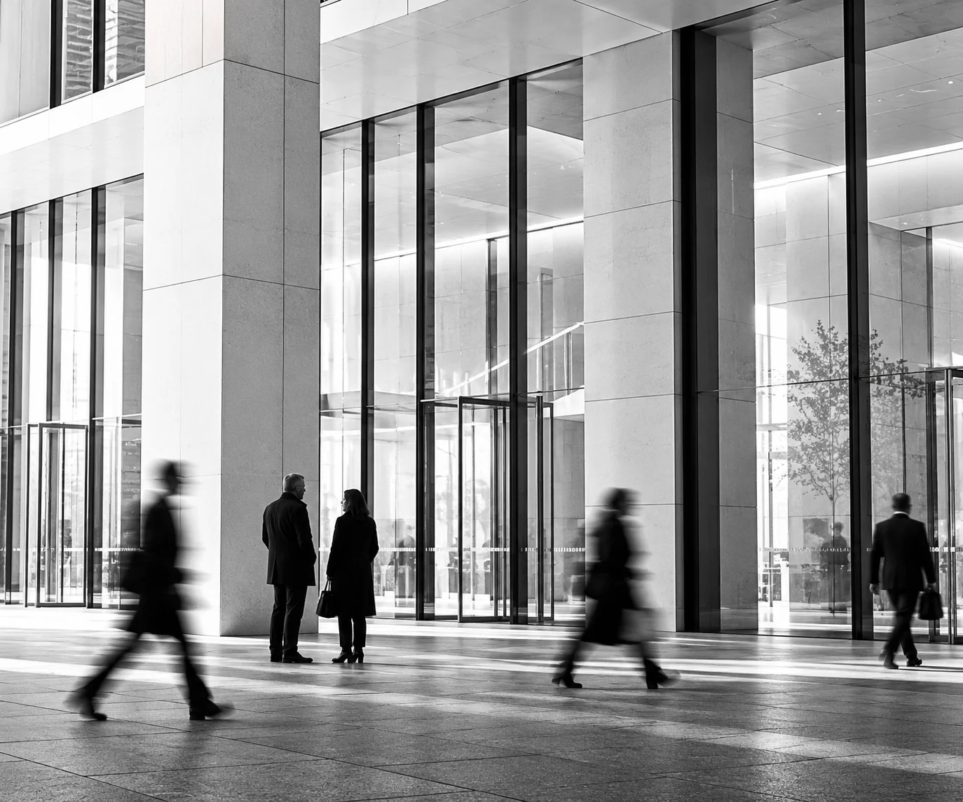 Black-and-white glass architecture with passing pedestrians blurred in motion